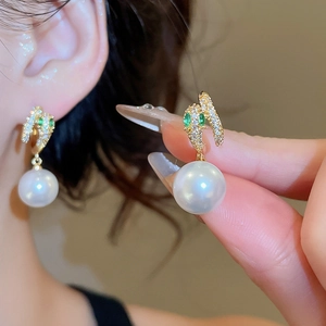 Close-up of 14K gold plated pearl earrings with micro-set zircon and emerald-green gems
