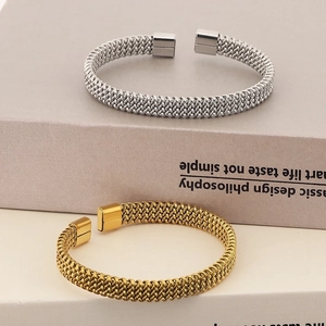 Detail van gevlochten roestvrijstalen armbanden in goud- en zilverkleurige afwerking