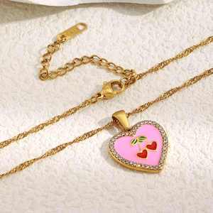 Detail of 18K gold-plated heart necklace featuring pink enamel, red cherry, and zircons