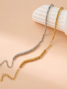 Detailed view of gold and silver beaded wave link bracelets on white marble decor