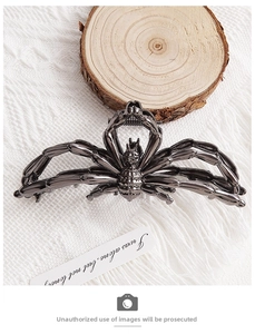 Macro detail of the dark gray metallic spider hair claw clip on a soft textured background