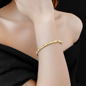 Detail of gold plated textured cuff bracelet with embedded crystals on female wrist