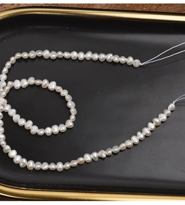 Macro shot of 4-5mm natural baroque pearls on a black tray showing luster and texture
