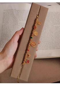 Detail of 24k gold plated bracelet with enamel Fu character charms on vintage book