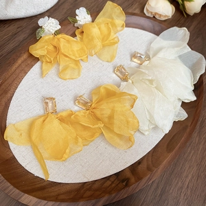 Detail of elegant mesh flower earrings with crystal accents on a rustic wooden tray
