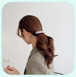 Detail of elegant lavender acrylic spring hair clip styled on a wavy brunette ponytail