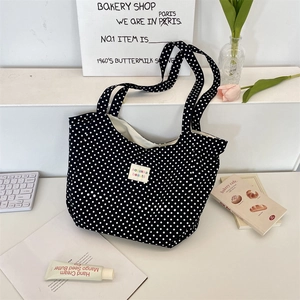 Polka dot canvas tote bag with woven logo label on a styled aesthetic desktop