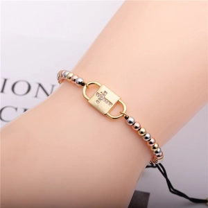 Three-tone beaded cross charm bracelet with adjustable black braided cord on wrist