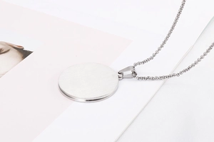 Close-up of a silver titanium steel round pendant necklace with a brushed metal finish