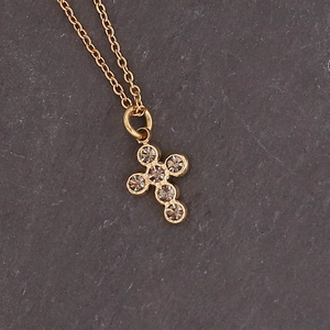 Macro shot of a golden cross necklace pendant with sparkling rhinestones on dark slate