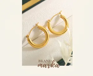 Detailed close-up of high-polish gold hoop earrings presented in a white textured jewelry box