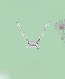 Detail of emerald cut rectangular zircon pendant on thin silver chain with four-claw setting