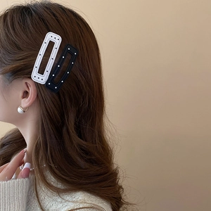 Close-up of black and white polka dot hair clips worn on wavy brown hair