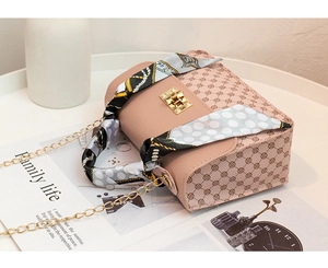 Detail of pink PU leather crossbody bag with metal chain strap and silk scarf handle