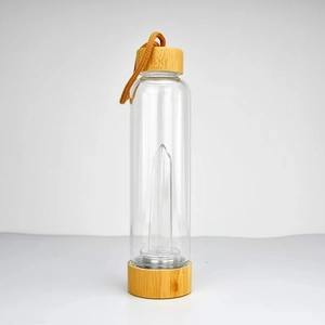 Detail shot of a crystal energy glass bottle with a bamboo lid and base on a grey background