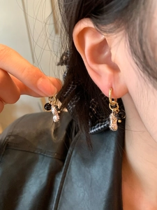 Gros plan d'une boucle d'oreille dorée en forme d'arachide avec perles noires