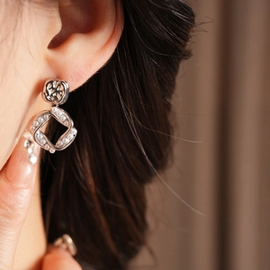 Close-up of square silver pearl earrings worn by a model with elegant french retro style