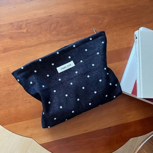 Detailed macro of dark blue denim polka dot pouch with a white woven simple wish label