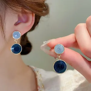 Detail of blue resin double hoop earrings with spiral texture and golden finish