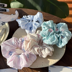 Pastel twill scrunchies with star embroidery and stripes set on a decorative plate