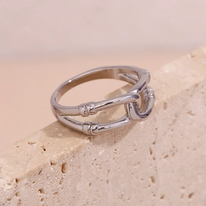 Macro shot of silver bamboo style double-layered hollow ring on a textured beige stone