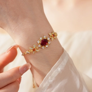 Detail eines Vintage-Goldarmbands mit rotem ovalem Edelstein und orangen Blumen