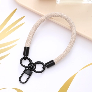 Detailed view of beige woven phone wrist strap with sturdy black metal spring buckle