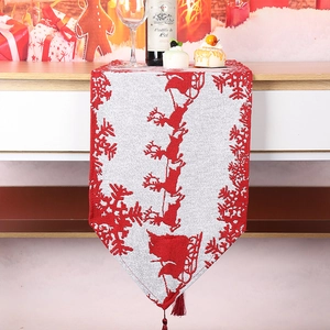 Detail of red and white Christmas table runner with reindeer motifs and red tassels