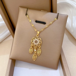 Macro detail of golden dreamcatcher necklace with hollow leaf pendants on silk background
