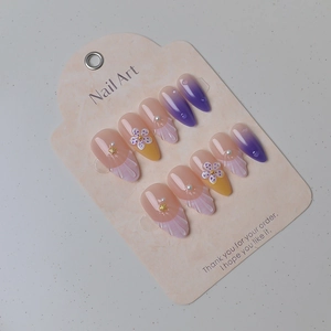 Detail view of almond press-on nails with purple gradient, 3D shells, and pearls