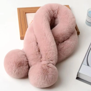 Écharpe rose en fausse fourrure avec pompons présentée avec des objets déco