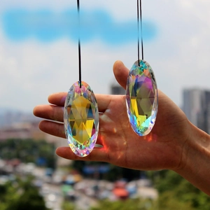 Macro shot of two large oval crystal prisms reflecting rainbow colors in hand