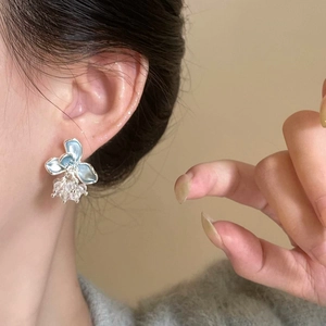 Close-up view of blue enamel flower stud earrings with delicate crystal bead drops.
