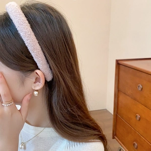 Detail of pink plush headband and matching pearl jewelry set worn by a female model