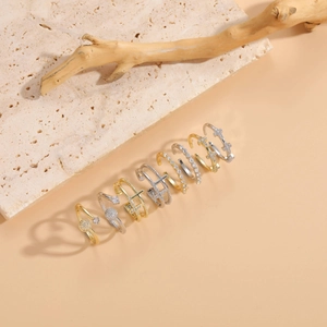 Close-up of elegant gold and silver cross rings with zircon stones on stone display
