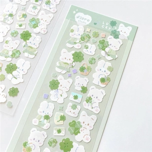 Close-up of cute white bear stickers with lucky clovers on green branded backcards