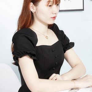 Model wearing gold heart necklace, earrings and bracelet set with minimalist cutout style