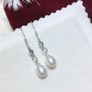Dettaglio degli orecchini con perle a goccia con ganci in argento e zirconi