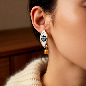 Macro shot of vintage style water-drop earrings with evil eye design on an elegant model