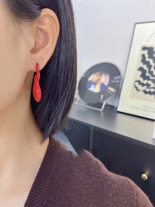 Close-up of red lava style fluid earrings worn by model with irregular drop glaze design