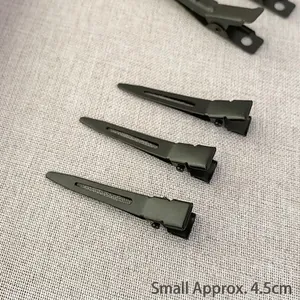 Detail of 4.5cm small black matte metal duckbill hair clip on linen fabric background