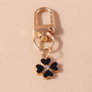 Detailed shot of golden keychain featuring black clover pendant with clear rhinestone center