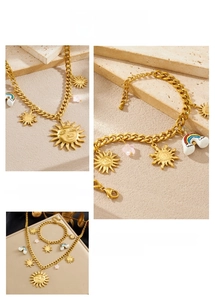 Detailed view of gold stainless steel necklace with sun and rainbow pendants