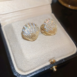 Macro shot of gold-plated shell earrings with cubic zirconia in a jewelry box