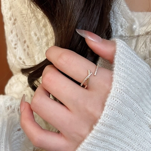 Close-up of elegant gold bypass ring with zircon bow on hand with knit sweater