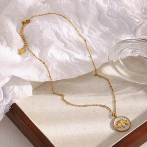 Détail macro du pendentif pièce abeille plaqué or 18K sur une chaîne à billes élégante