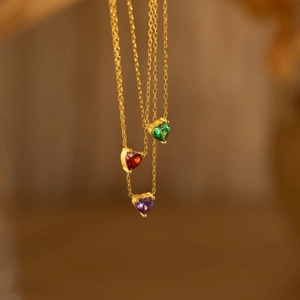 Golden stainless steel necklace with three heart-shaped birthstone pendants in green, red, and purple