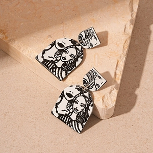 Detailed view of acrylic arch earrings with black and white abstract face illustration