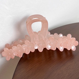 Detail of pink floral hair claw clip made of translucent resin on wooden surface