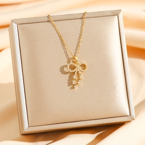 Elegant gold bow pendant necklace with crystals on silk background for women